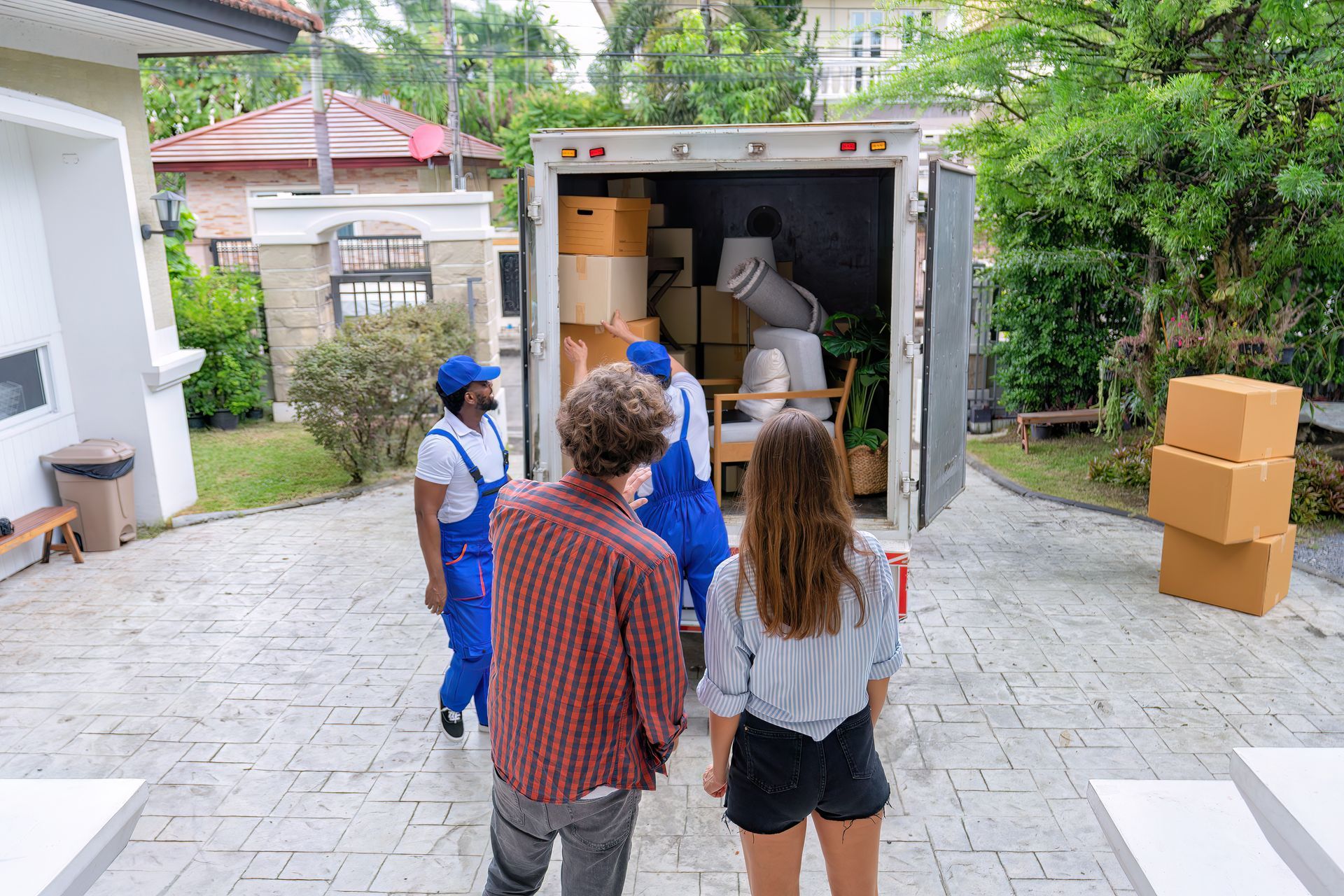 A group of people are standing in front of a moving truck filled with boxes.