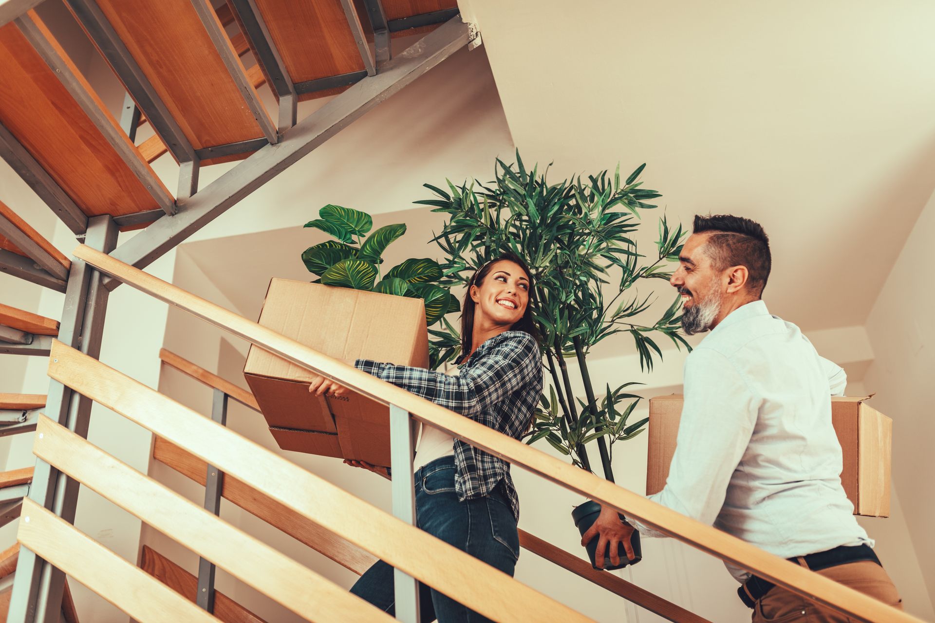 A man and a woman are carrying boxes up a set of stairs