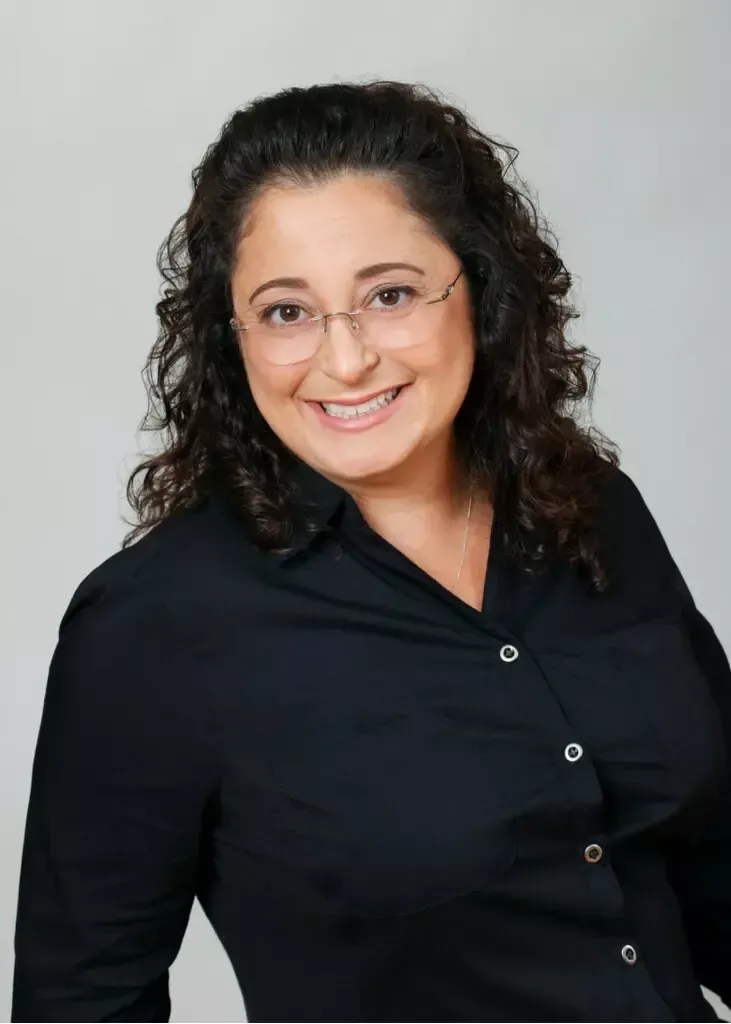 A woman wearing glasses and a black shirt smiles for the camera