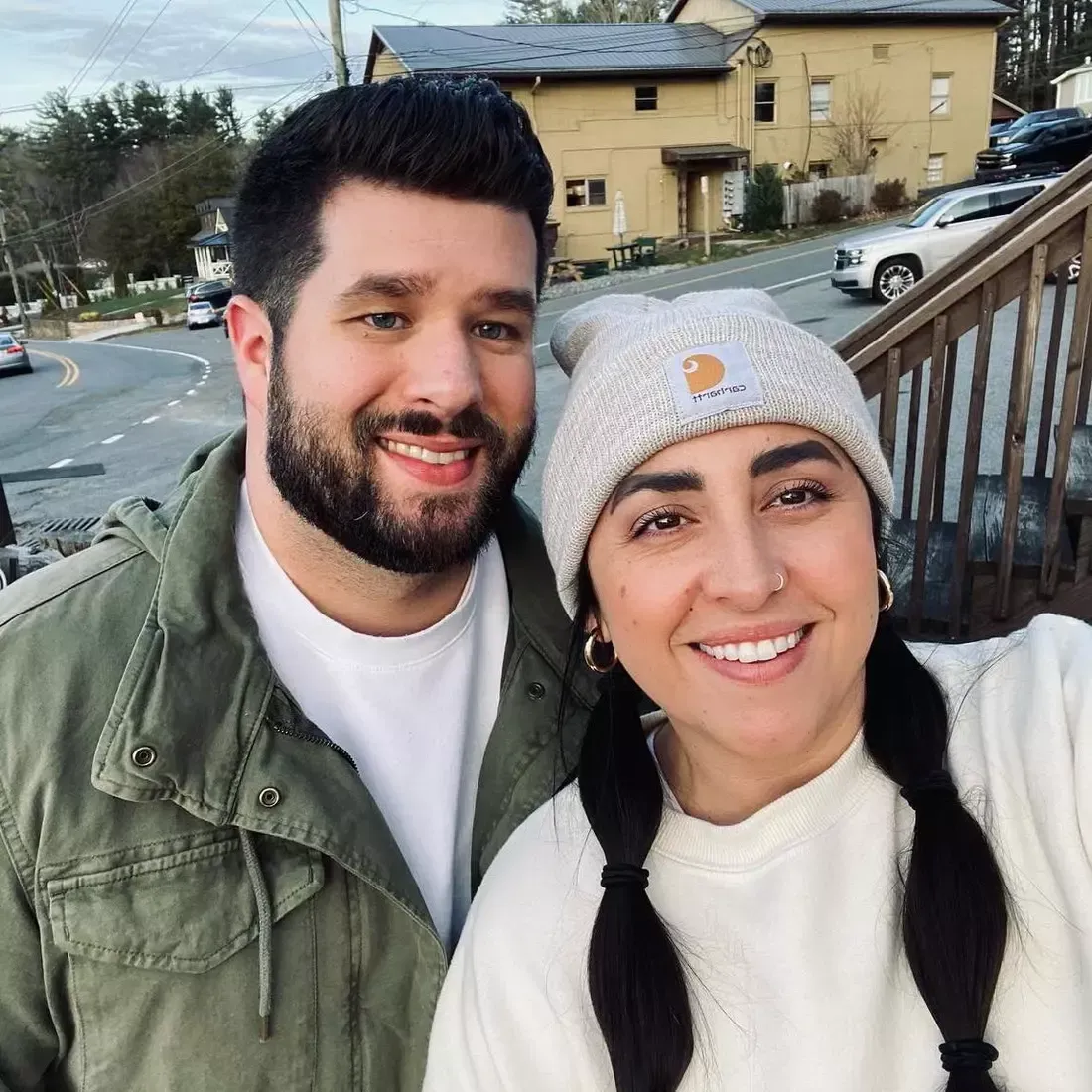 A man and a woman are posing for a picture in front of a building.