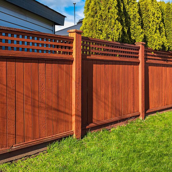 Nice new wooden fence around house. Wooden fence with green lawn. Street photo