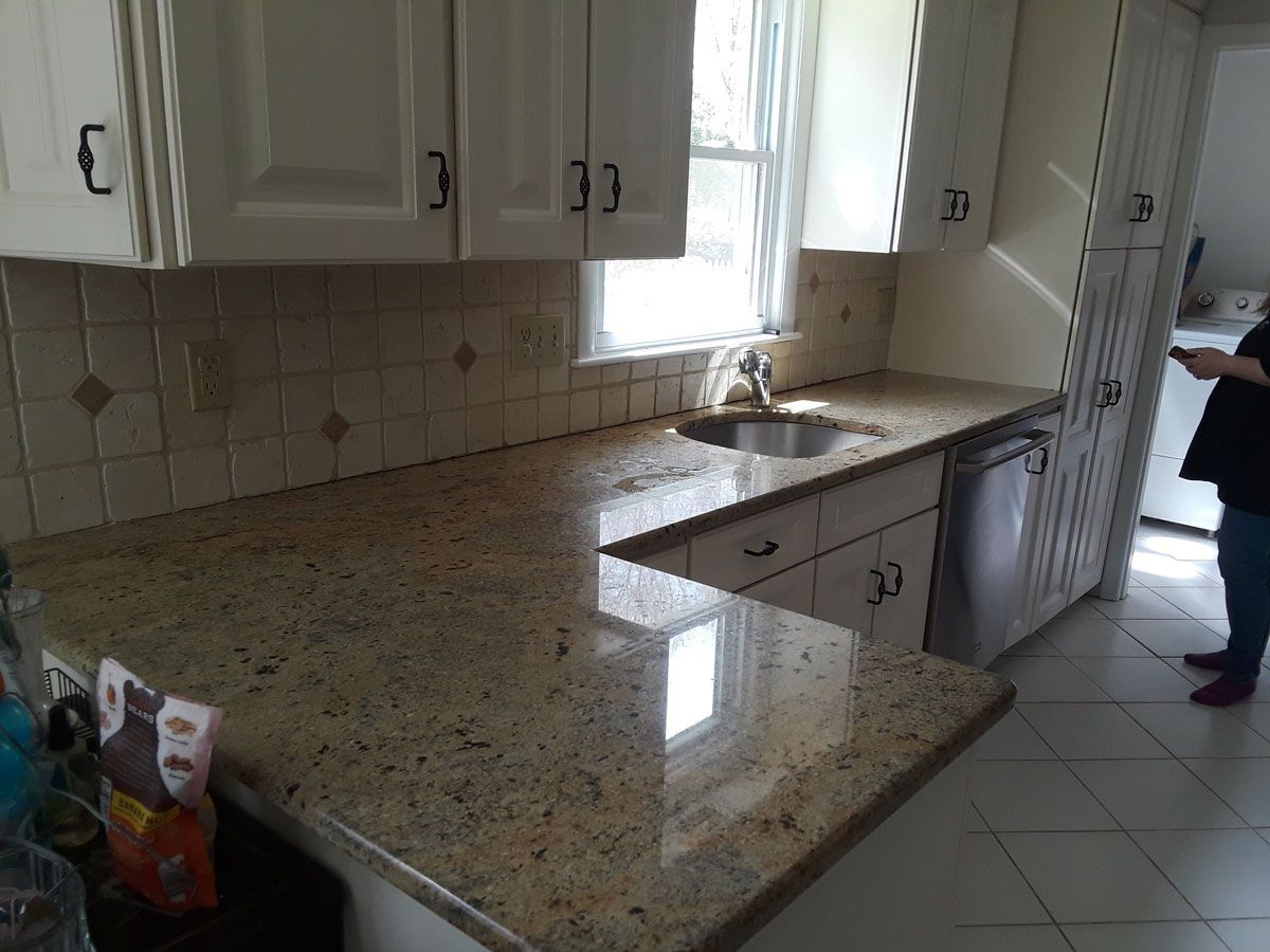 A kitchen with granite counter tops and white cabinets