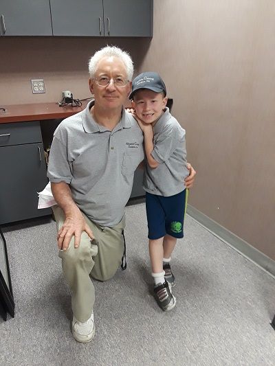 A man and a boy are posing for a picture in a kitchen.