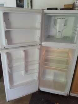 An empty refrigerator with the door open in a kitchen.
