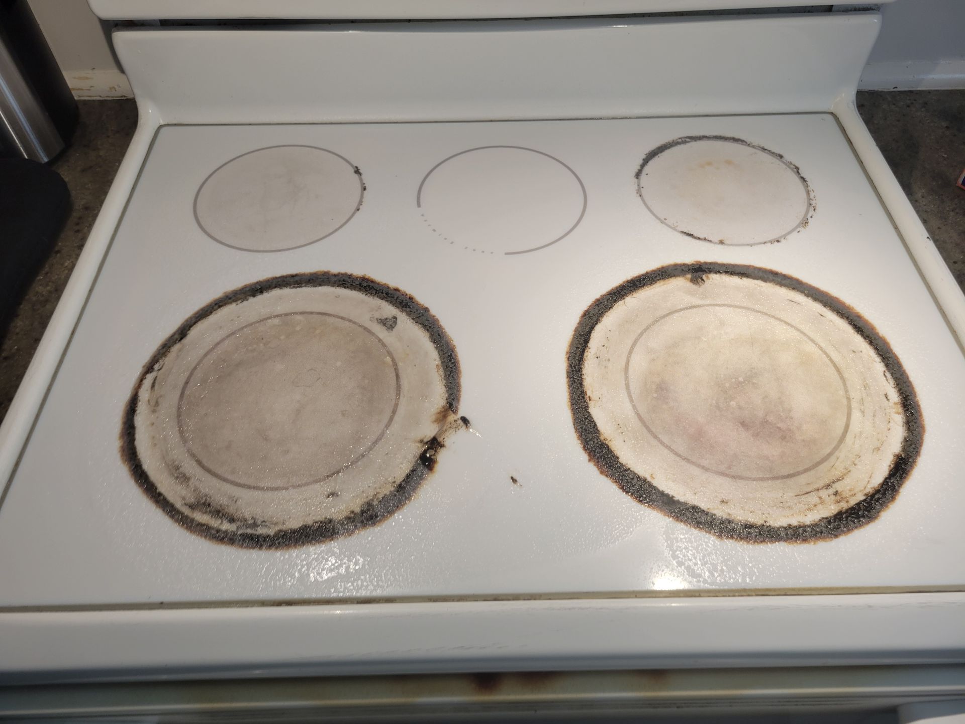 A white stove top with dirty circles on it