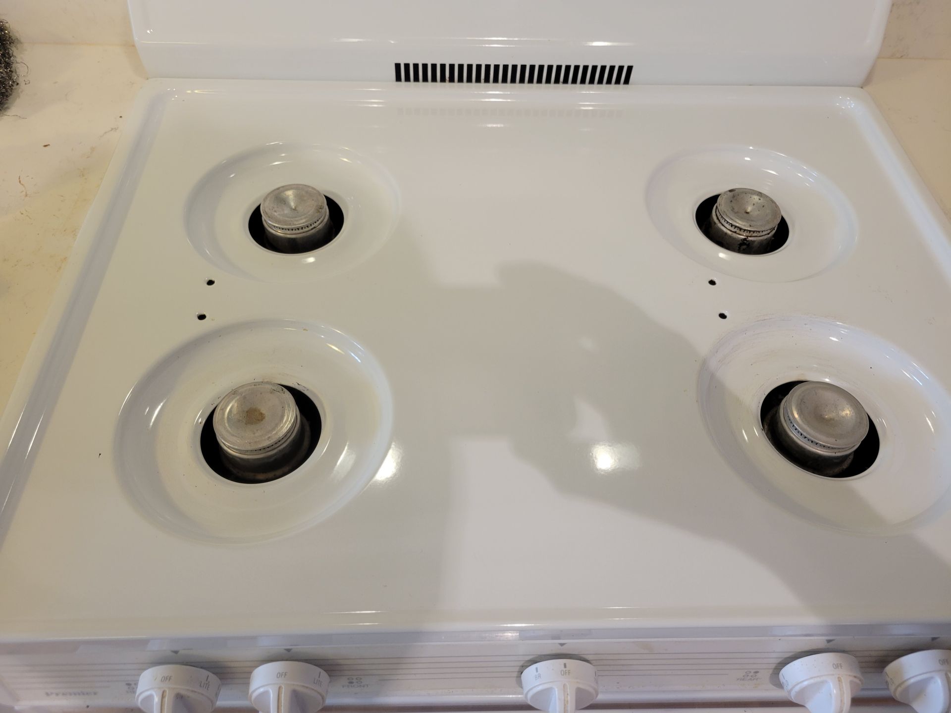 A white stove top with four burners on it