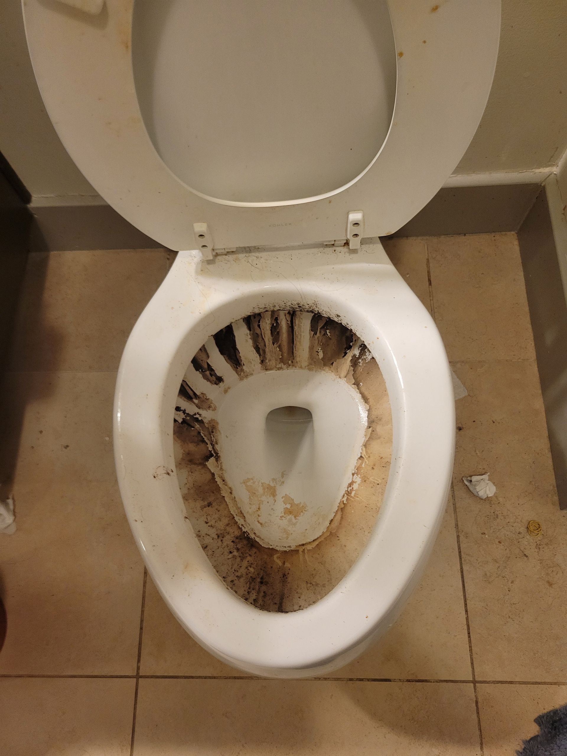 A dirty toilet sits on a tiled floor