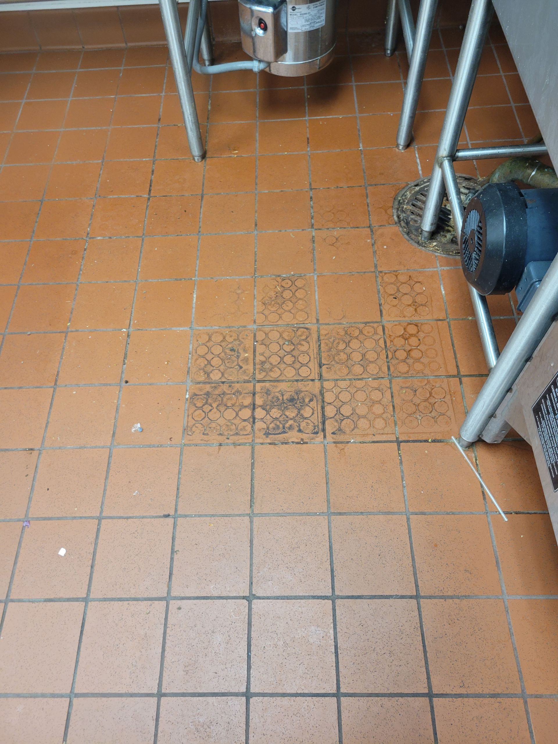 A tiled floor in a kitchen with a sink in the background
