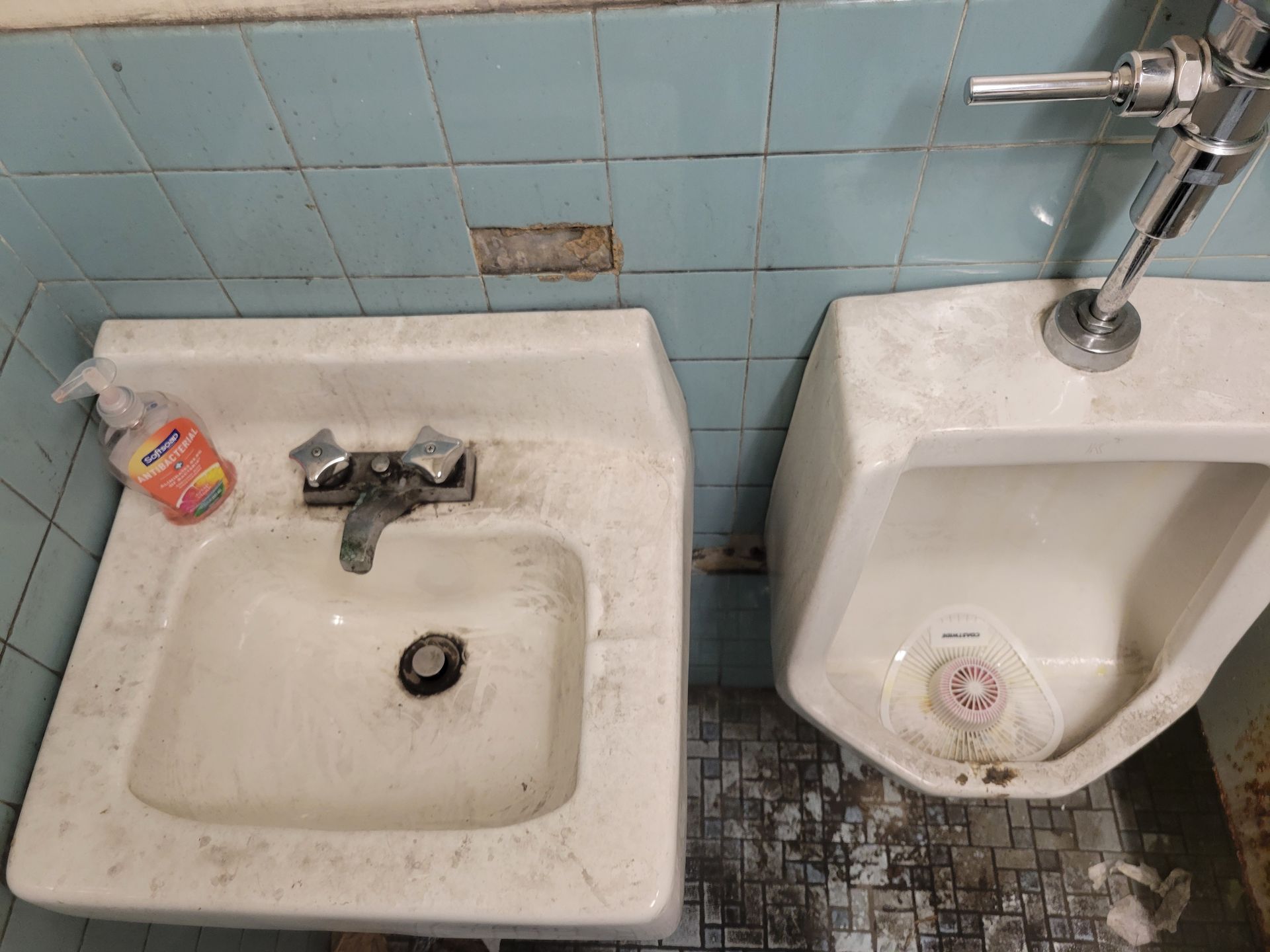 There is a sink and a urinal in the bathroom.