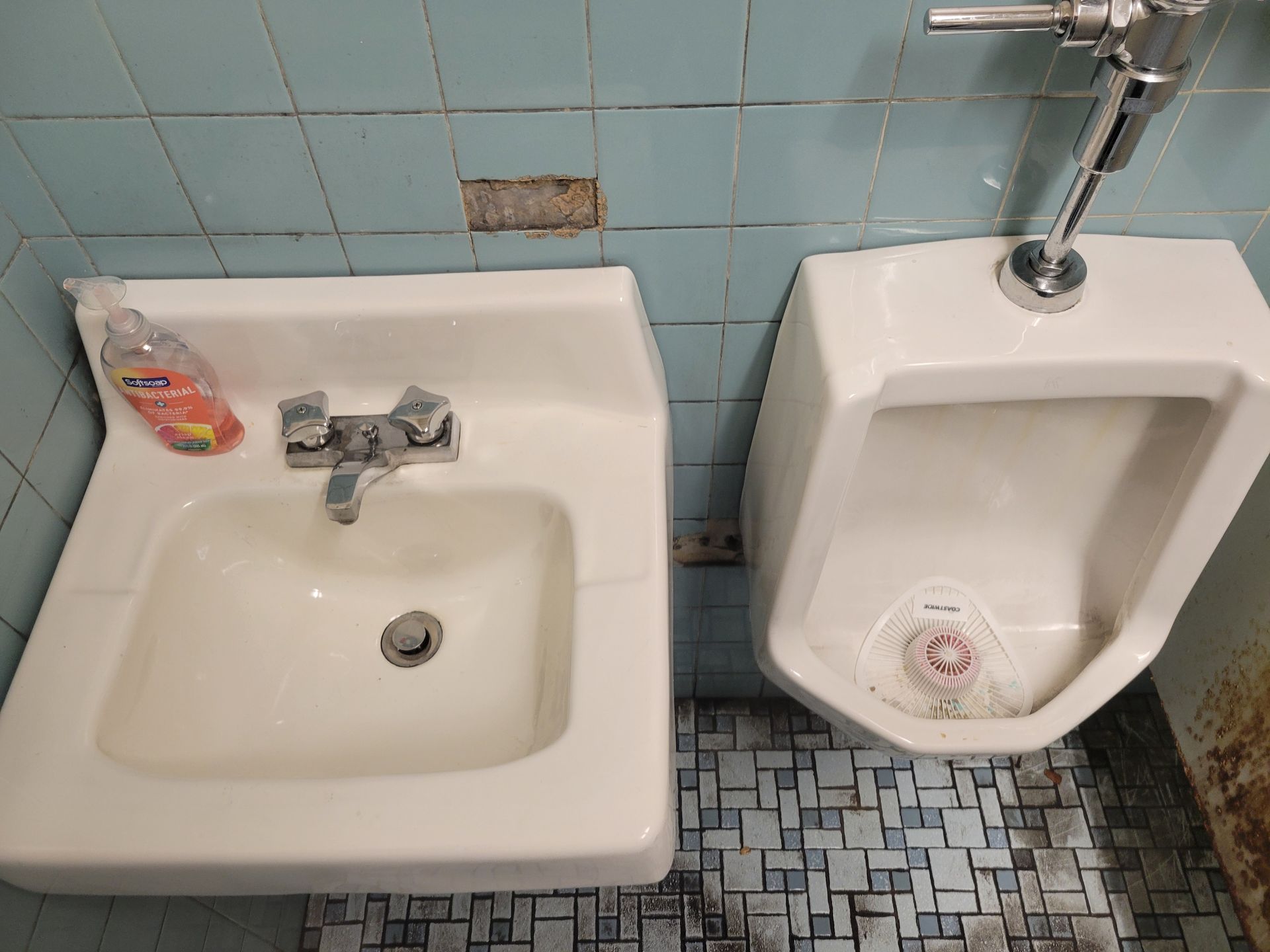 A bathroom with a sink and urinal next to each other