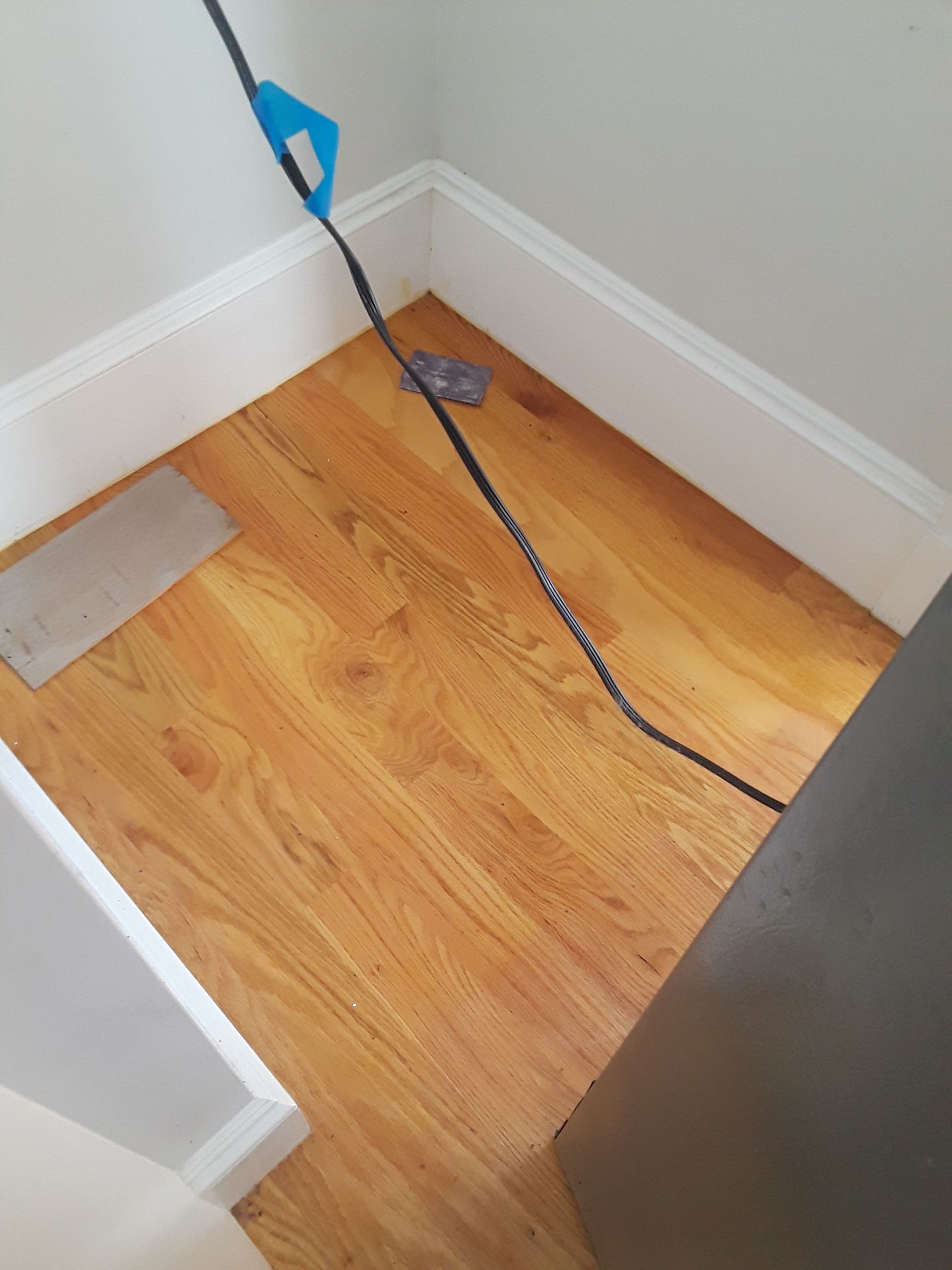 A wooden floor with a black cord hanging from it