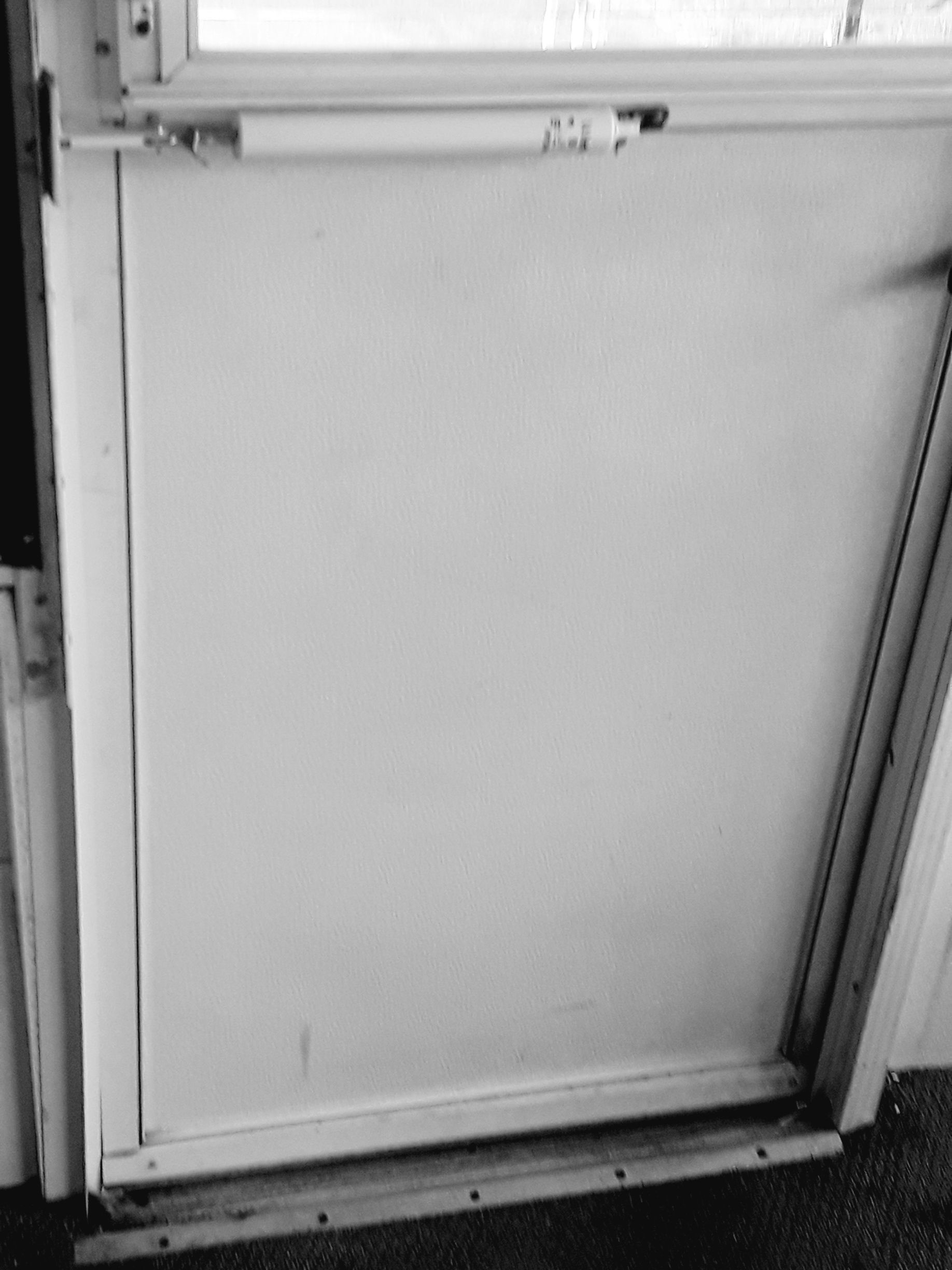 A black and white photo of a white door with a window.