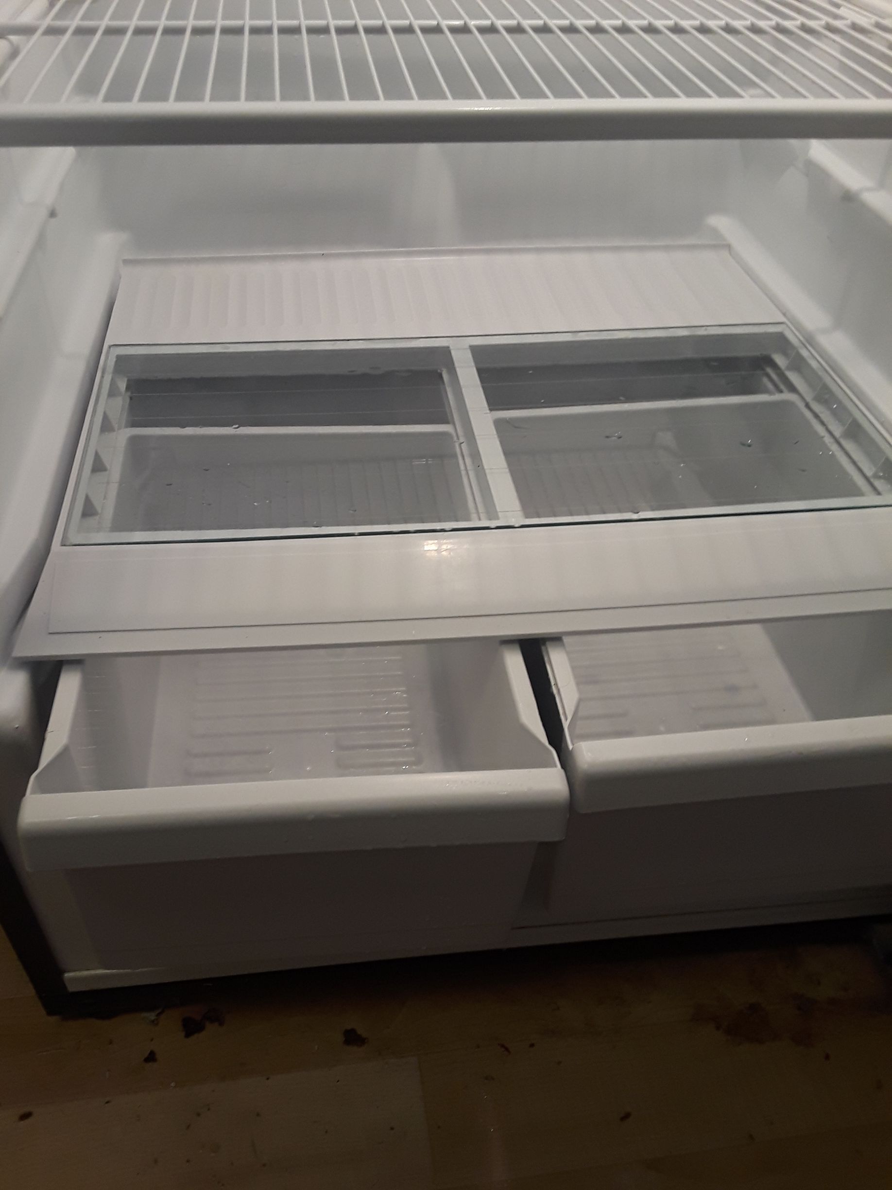 The inside of an empty refrigerator with drawers and shelves.