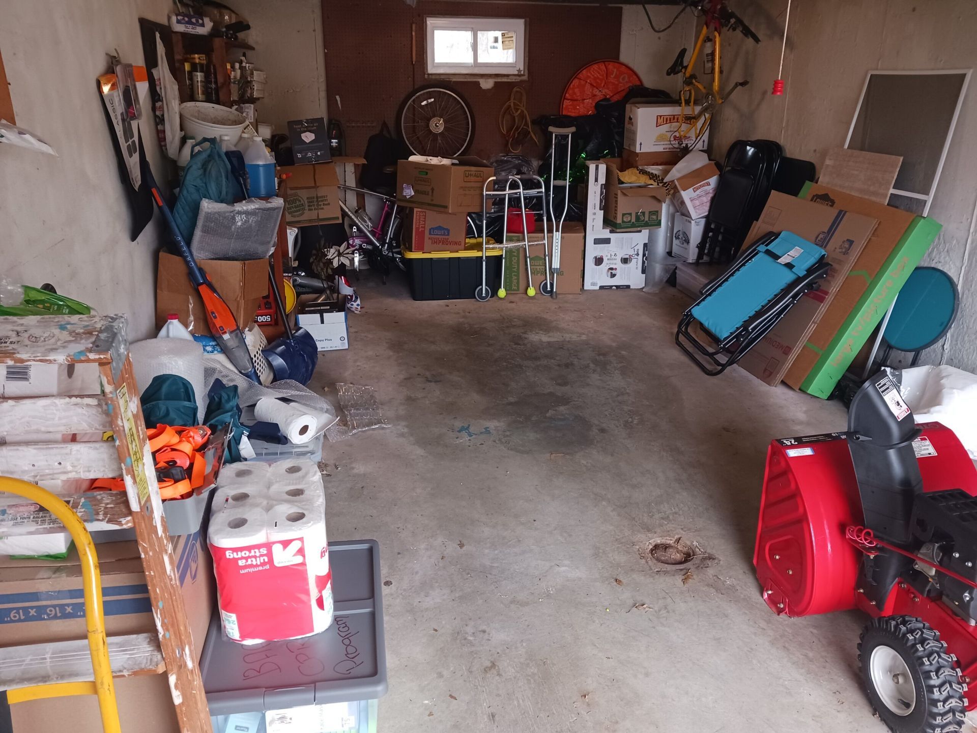 A garage filled with lots of items including a snow blower