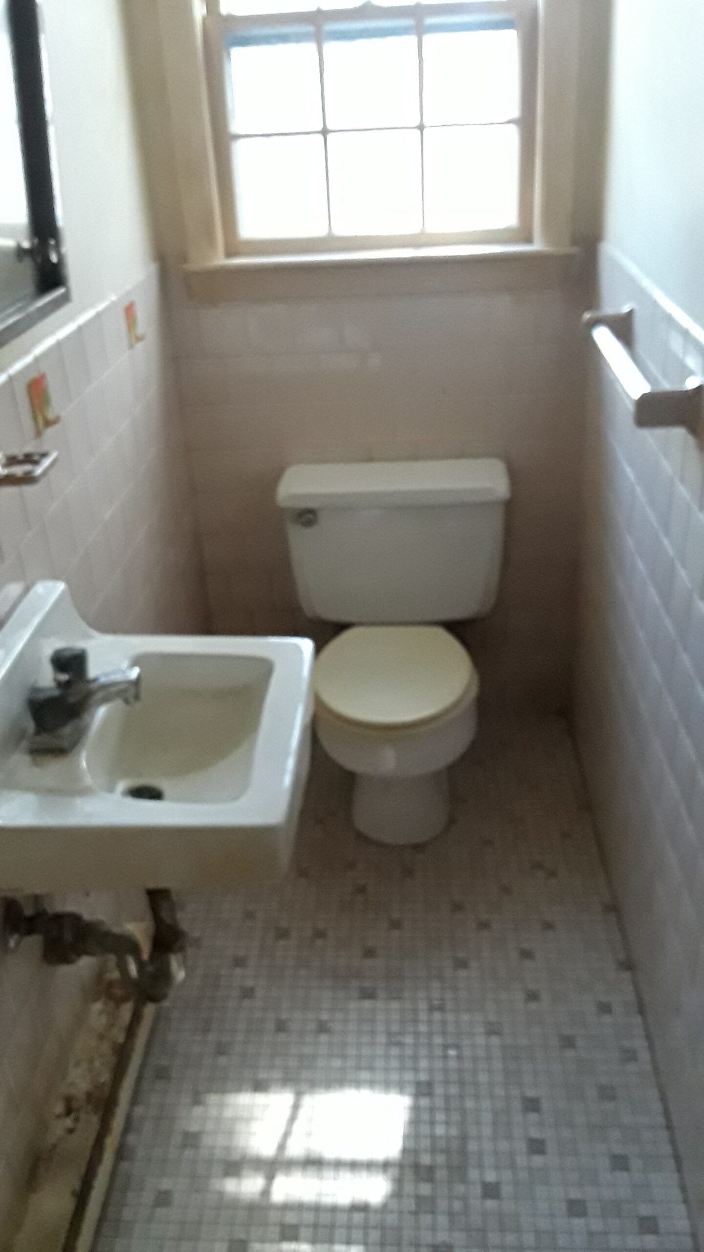 A bathroom with a toilet , sink and window.
