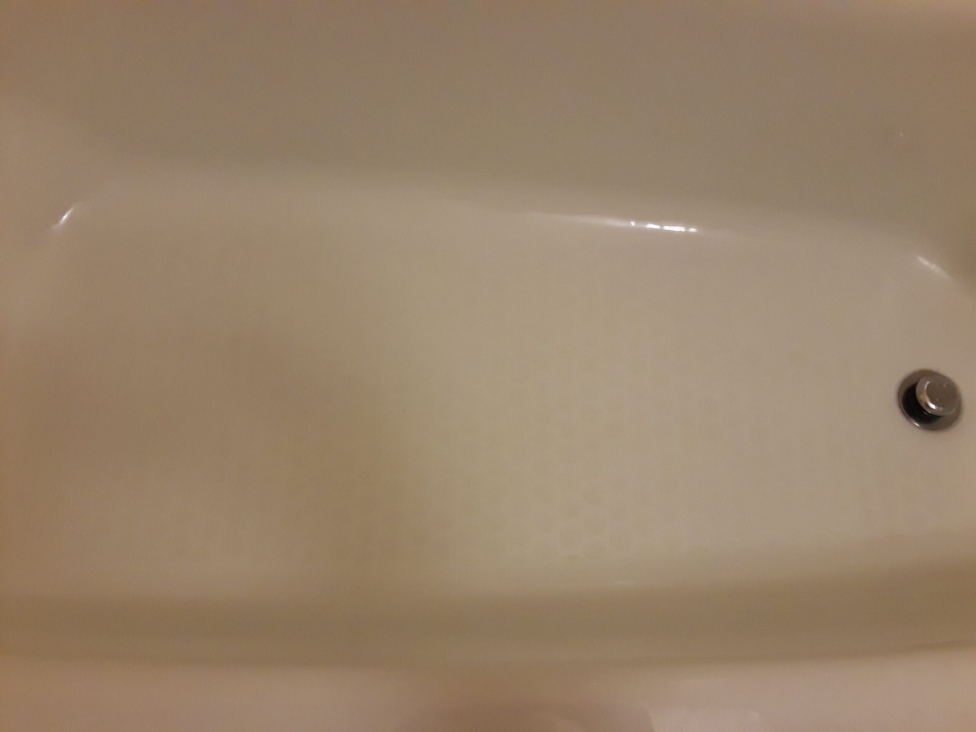 A white bathtub with a drain in the middle of it.