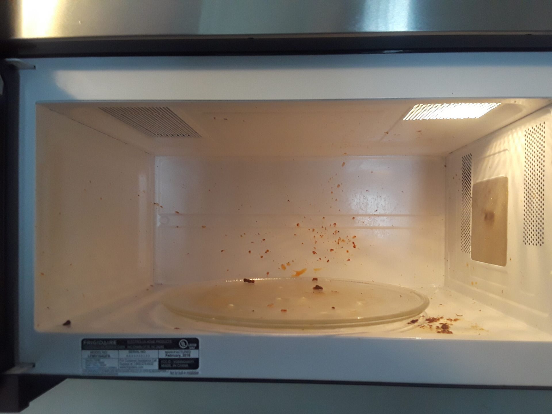 The inside of a microwave oven with a lot of crumbs on it.