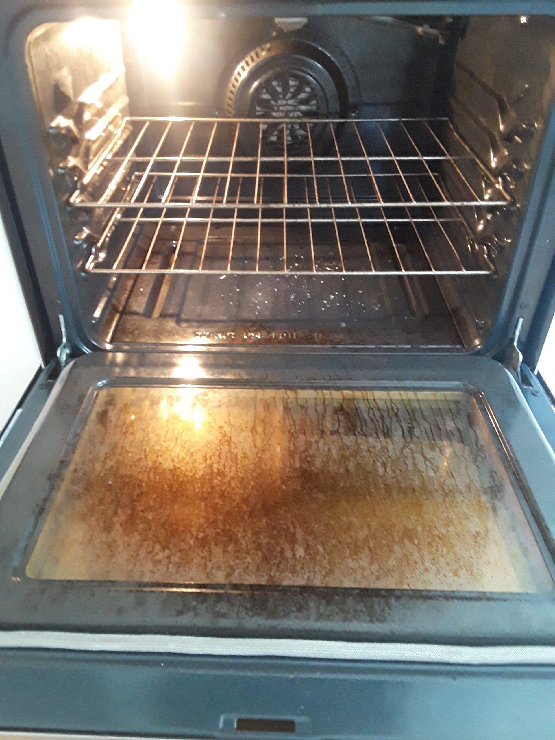 The inside of a dirty oven with a car parked in the background.