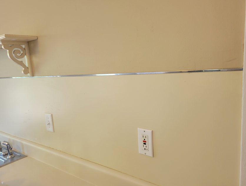 There is a shelf on the wall above the sink in the kitchen.