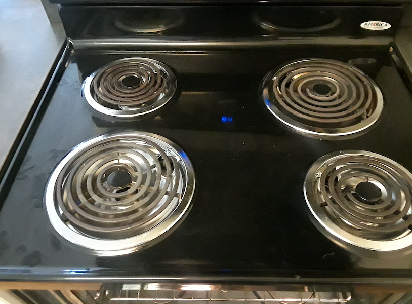 A black stove top with four burners on it