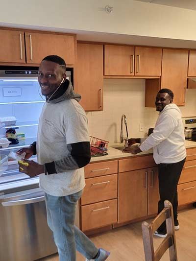 A man is standing in a kitchen next to a refrigerator.
