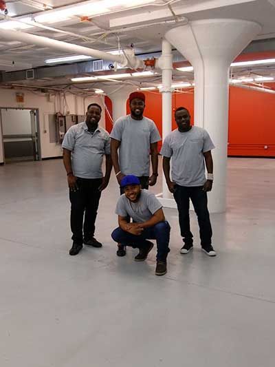 A group of men are posing for a picture in an empty room.