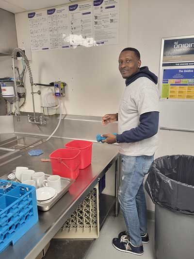 A man is standing in a kitchen washing dishes.