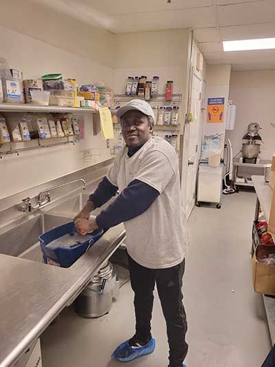 A man is washing his hands in a kitchen sink.