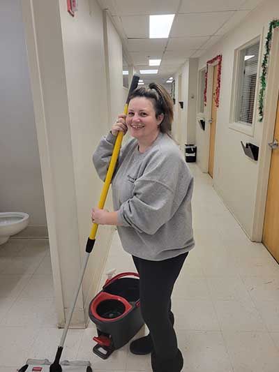 A woman is cleaning a hallway with a mop and bucket.