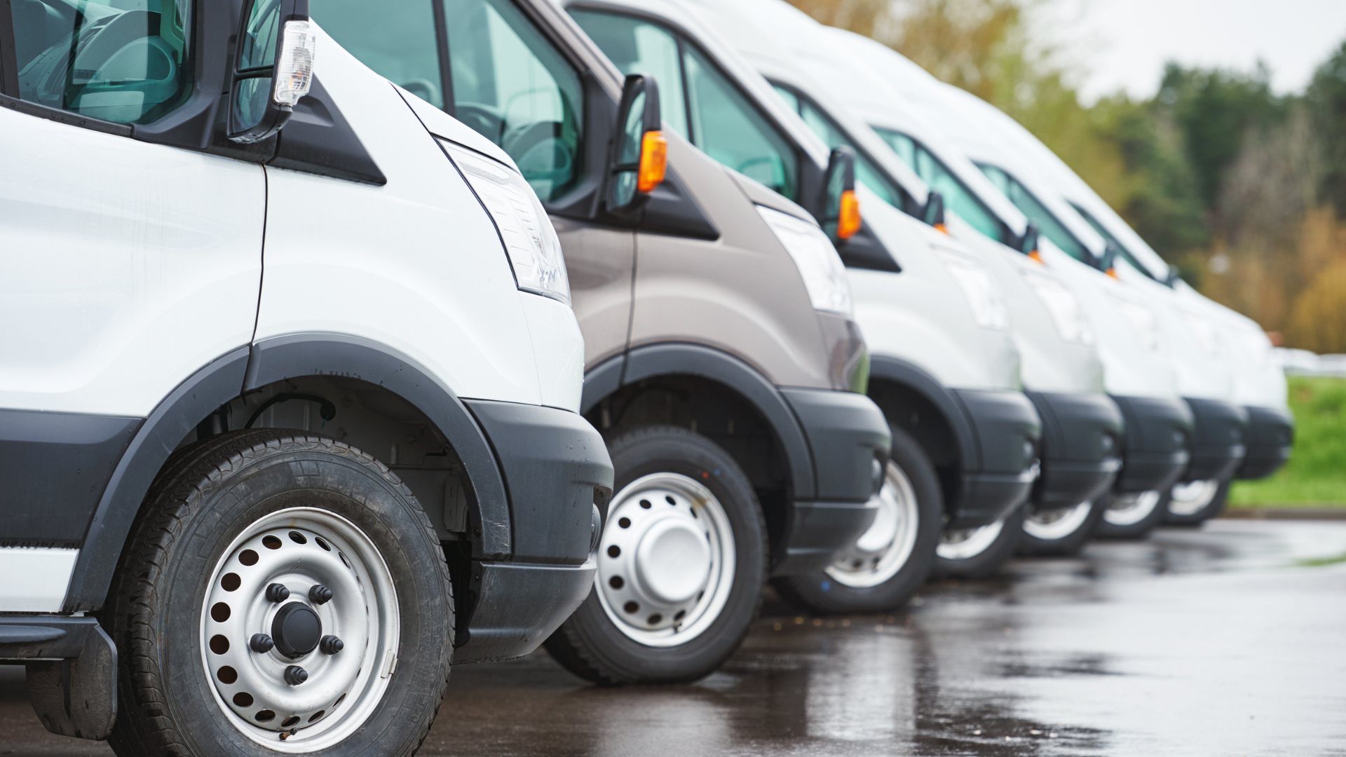 A row of white vans parked next to each other in a parking lot.