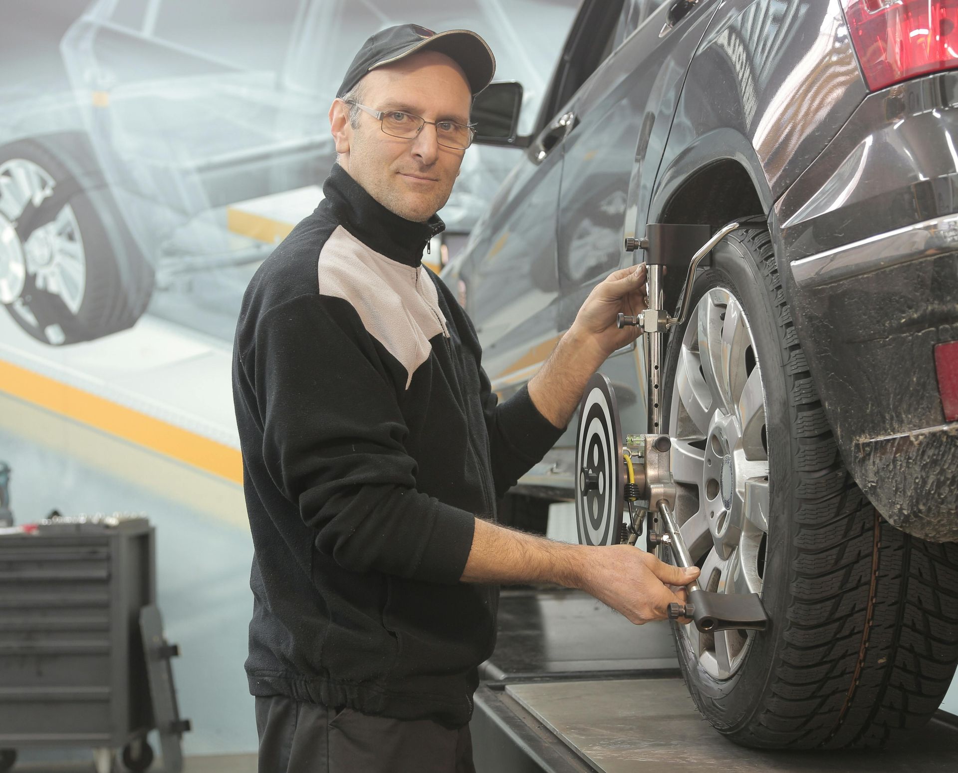 A man is adjusting a tire on a car in a garage.
