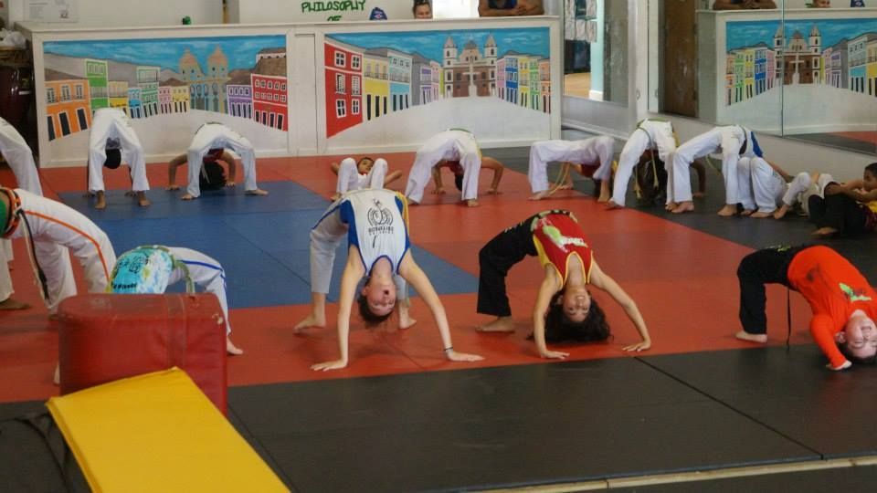 a group of children are doing capoeira exercises in a gym .