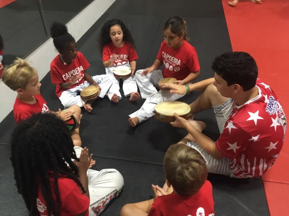 a group of children are sitting in a circle playing drums .