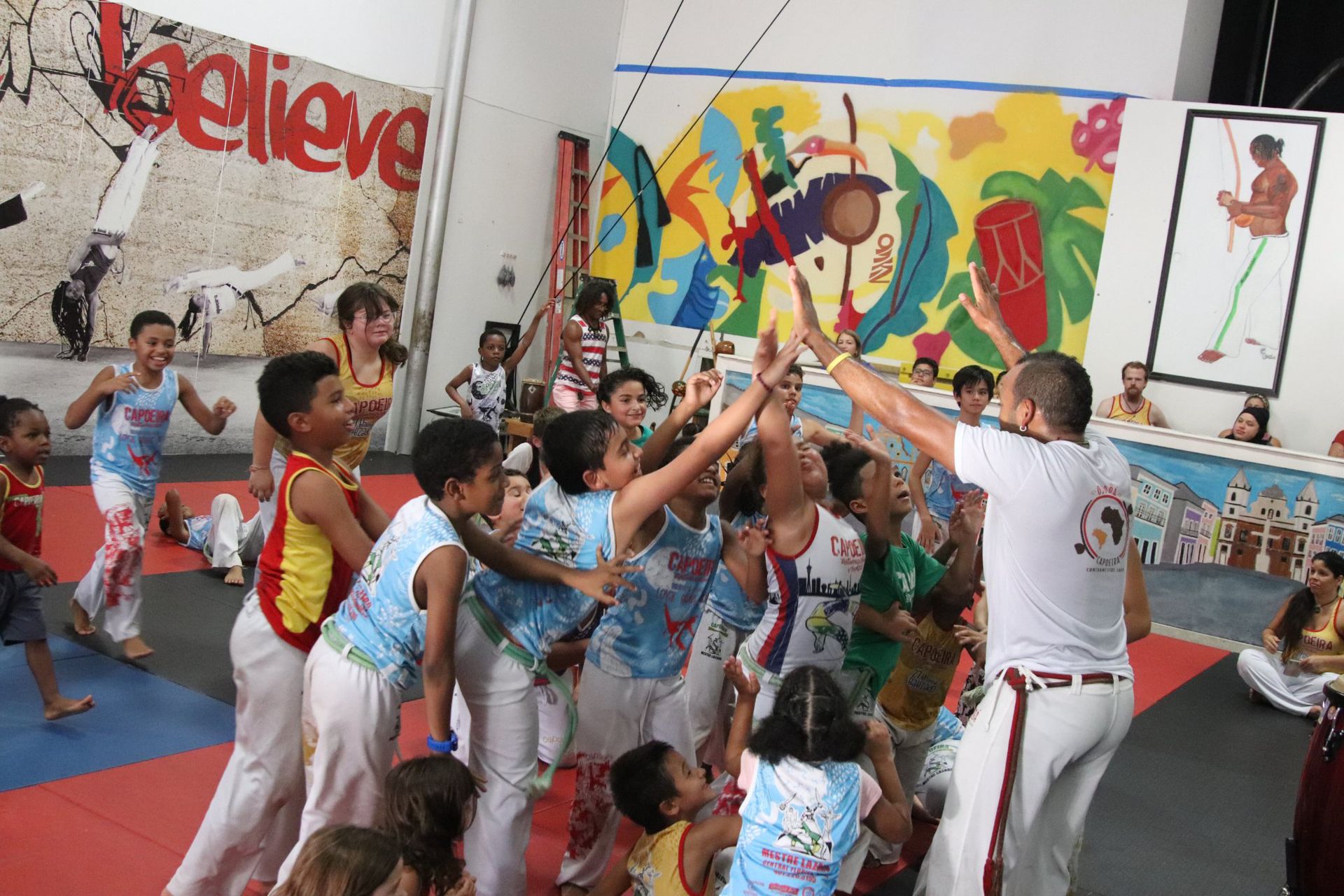 a group of children are dancing in front of a wall that says believe