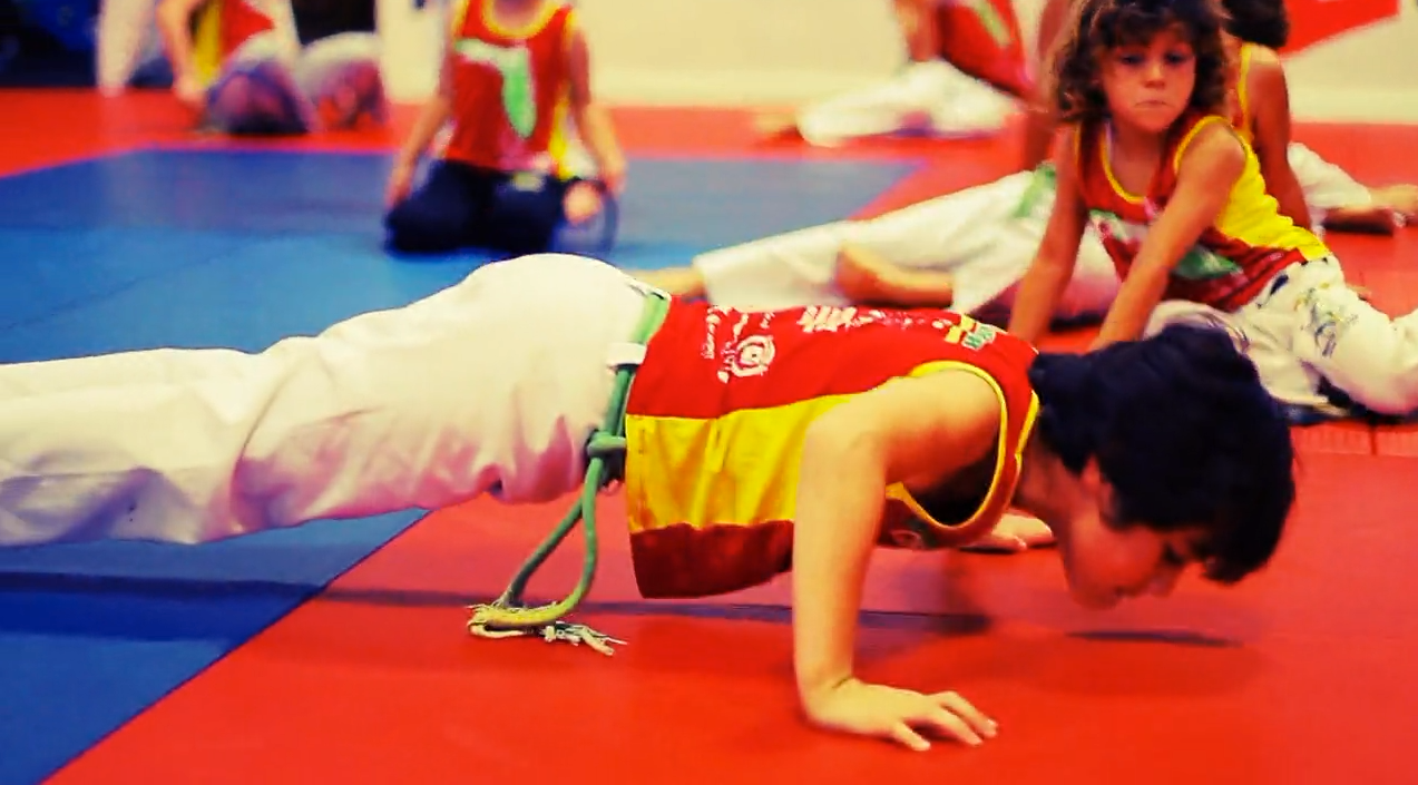 a group of children are doing push ups on a red and blue mat .