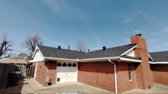A brick house with a black roof and a chimney.
