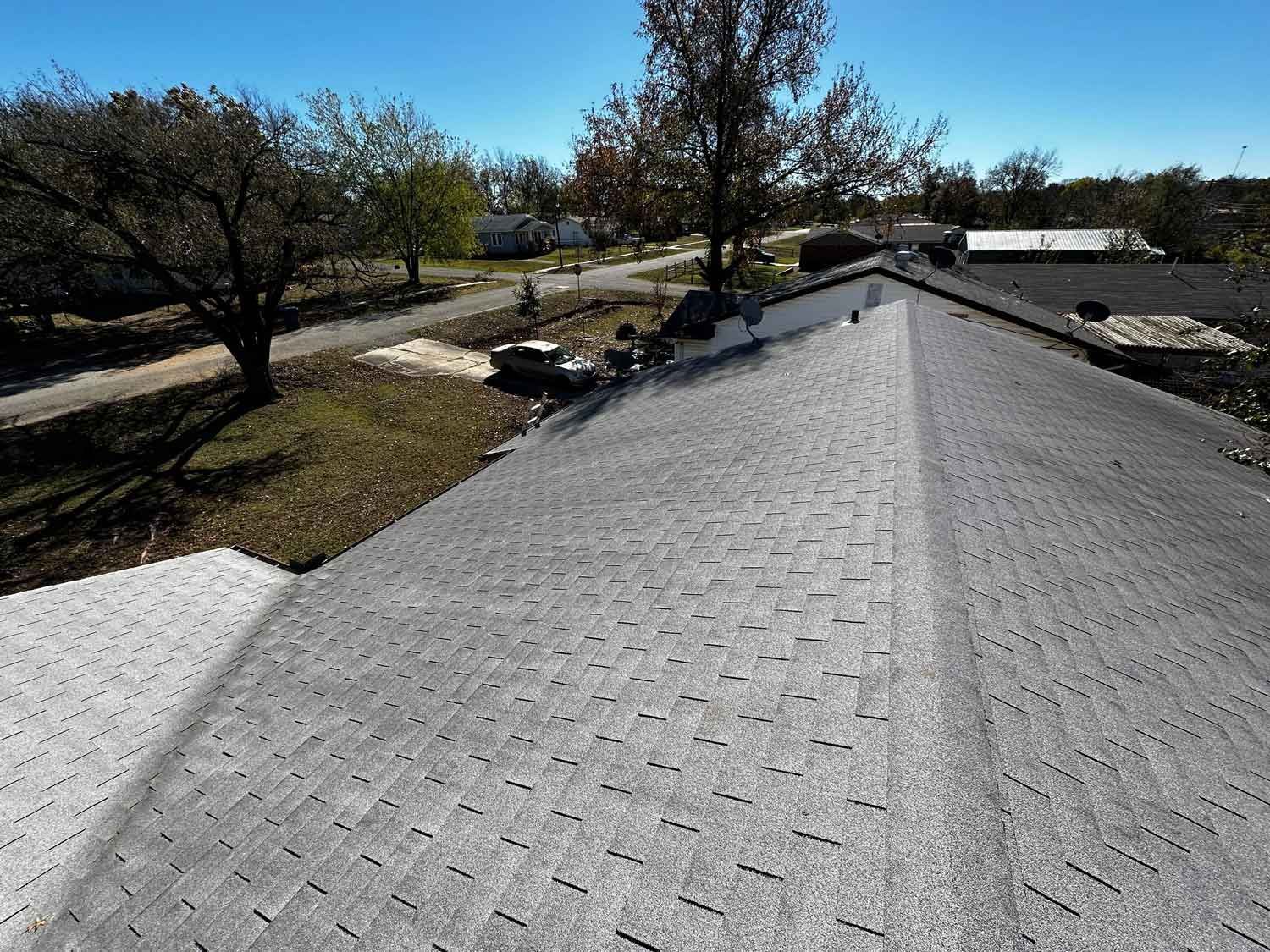 An aerial view of a roof of a house with trees in the background.
