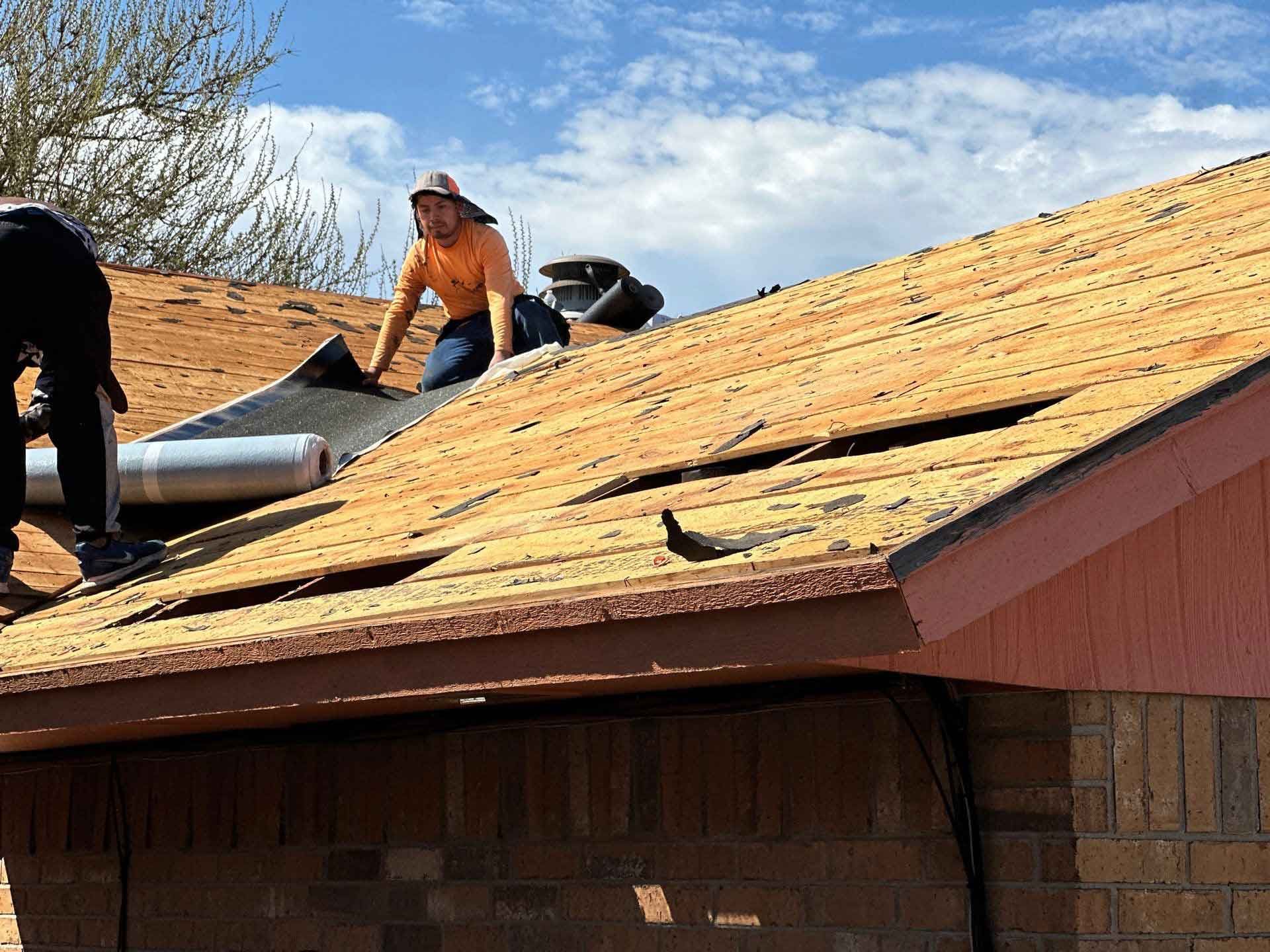 Two men are working on the roof of a house.