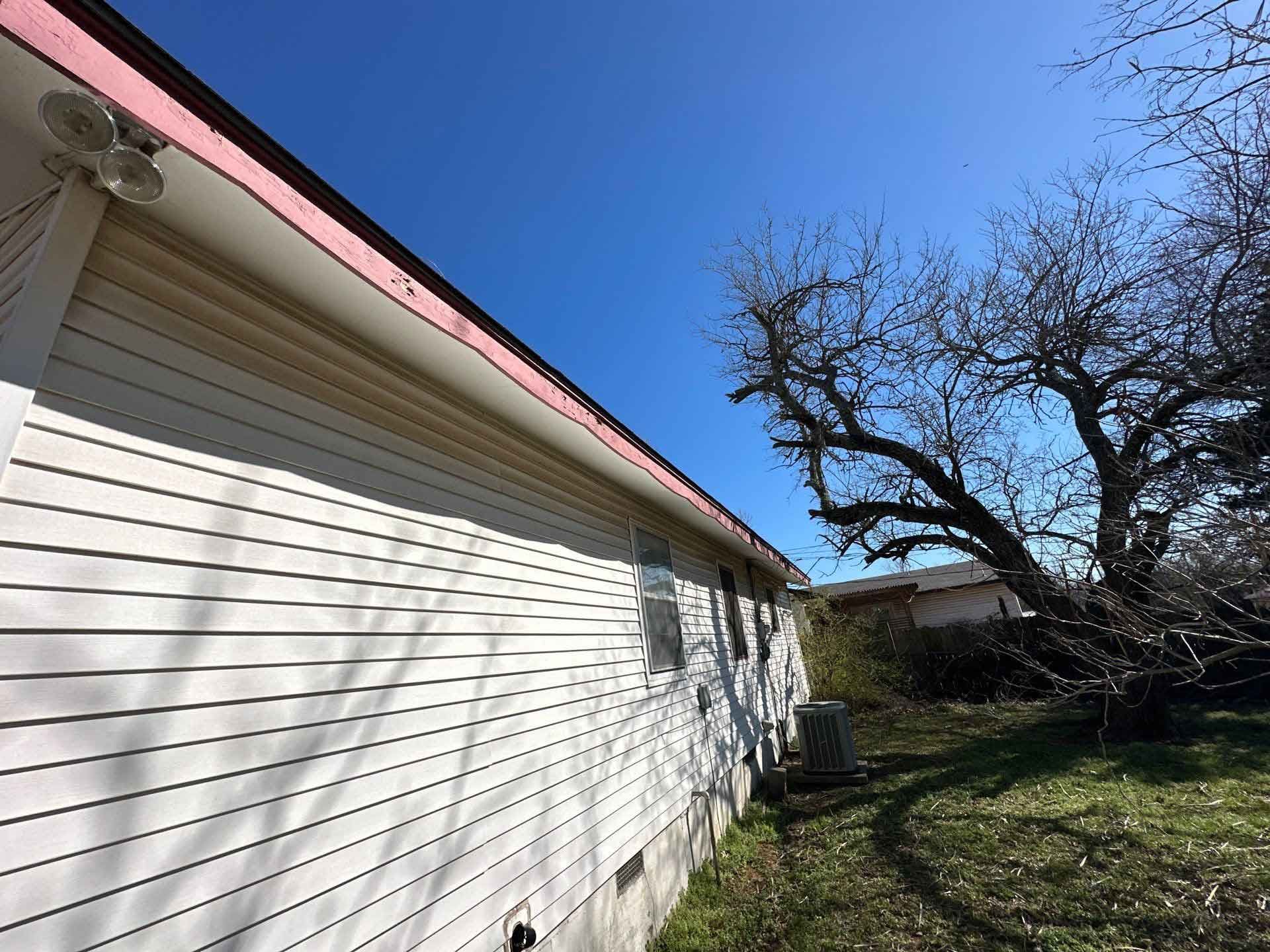 A white house with a red roof and a tree in the background
