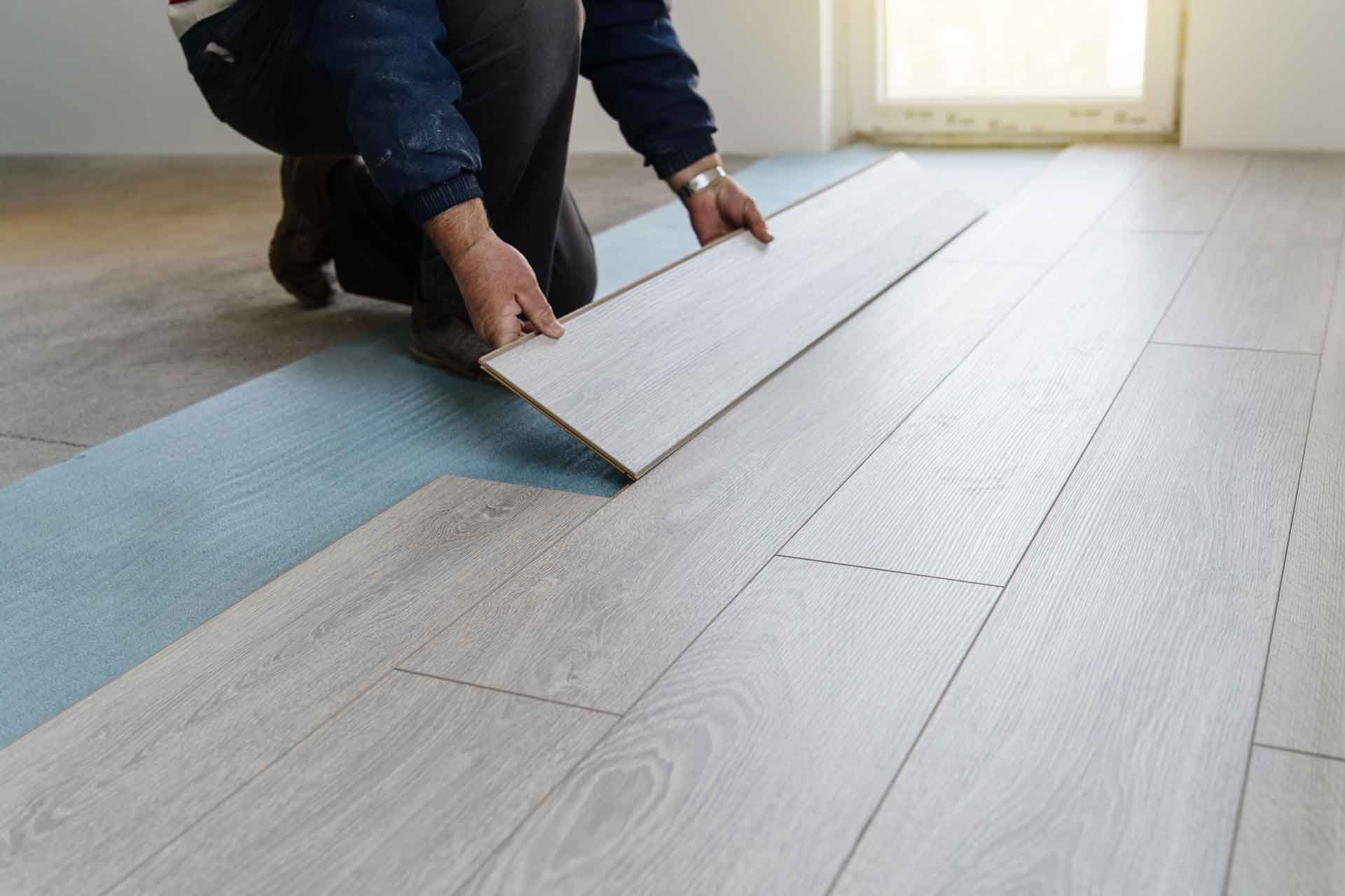 A man is installing a wooden floor in a room.