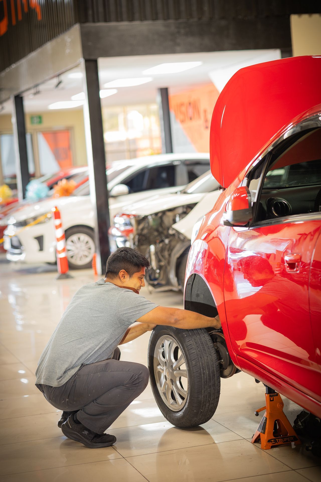 Un hombre está trabajando en un coche rojo en un garaje.