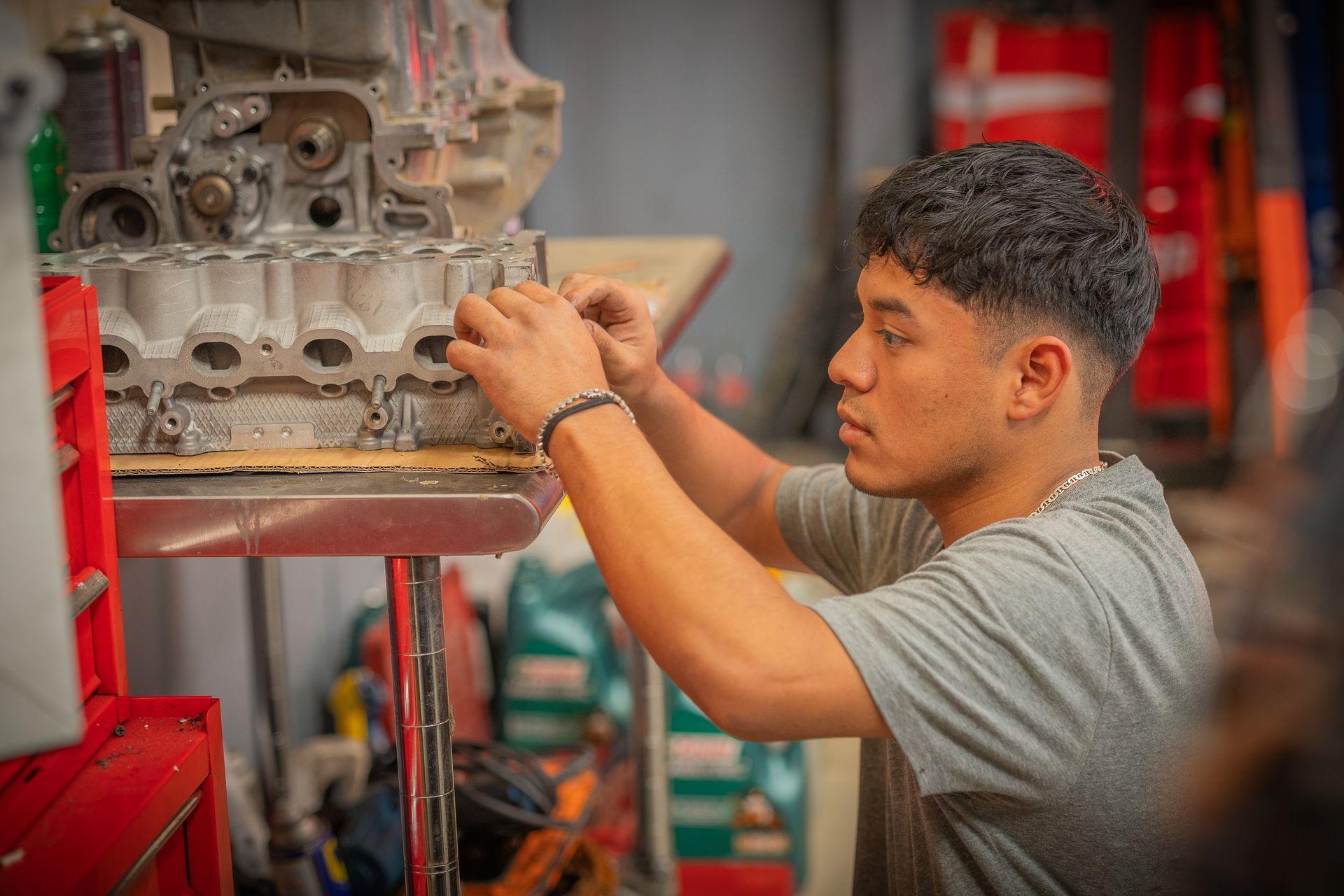Un joven está trabajando en el motor de un coche en un garaje.