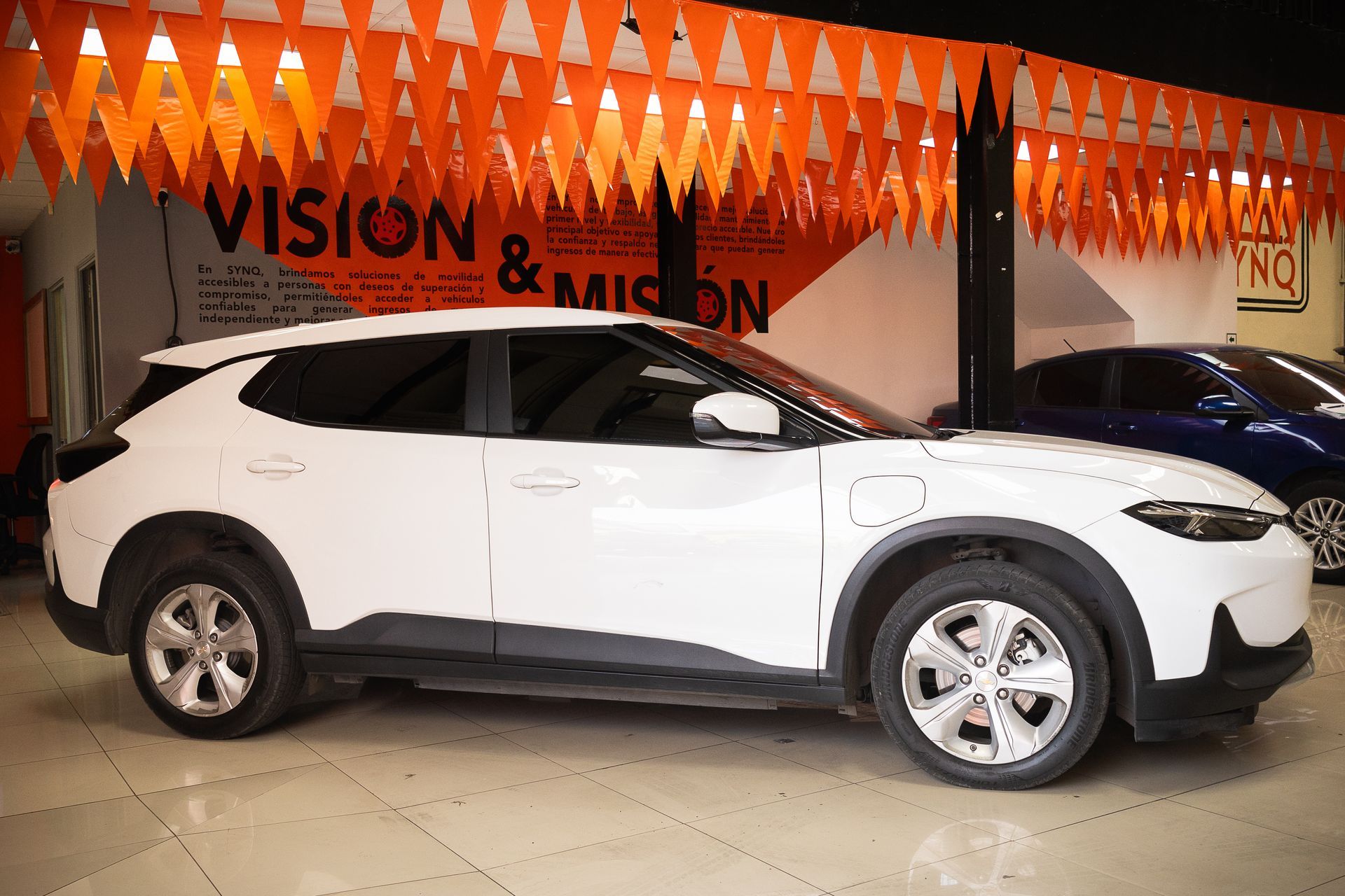 Un coche blanco está aparcado delante de un cartel de visión y misión.