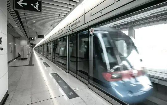 Tren circulando a toda velocidad por una moderna estación de metro.