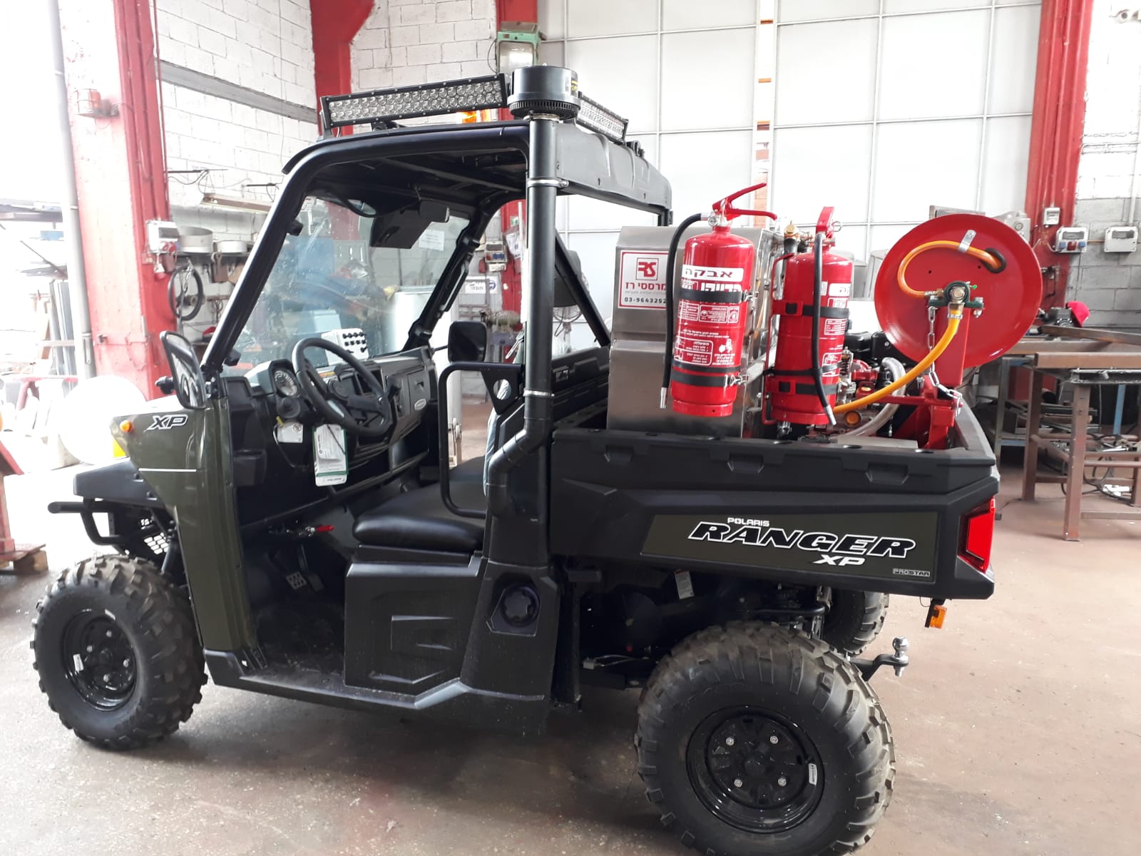 A utility vehicle with fire extinguishers in the back is parked in a garage.