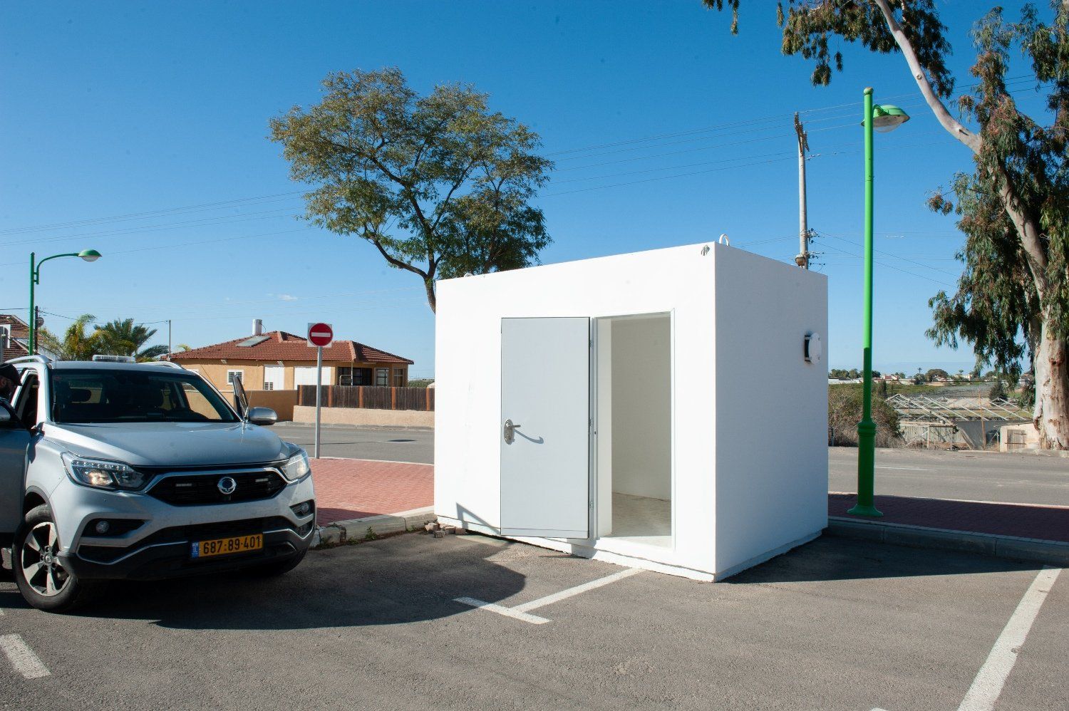 A car is parked in a parking lot next to a small white Shelter