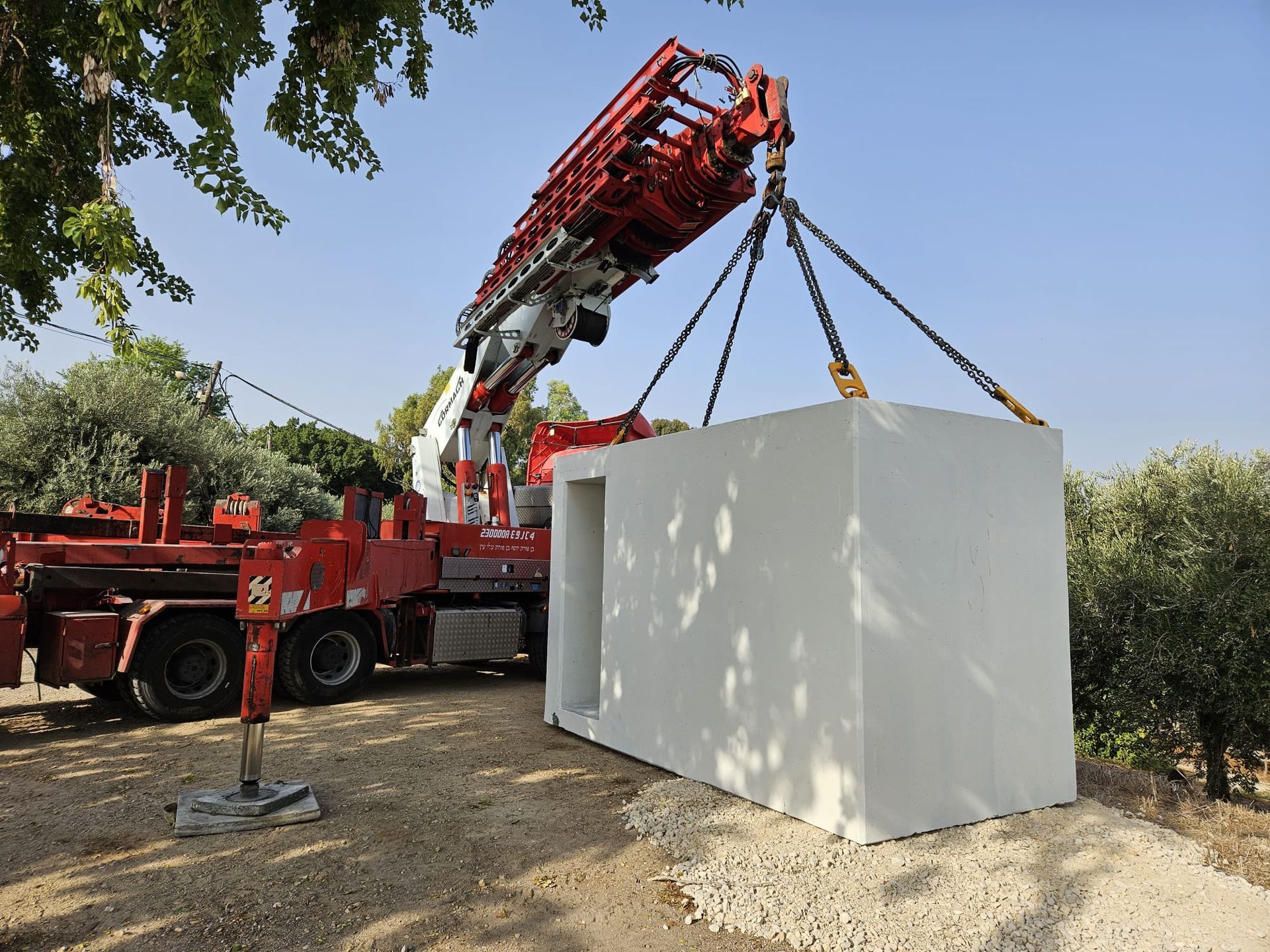 A red crane is lifting a large white shelter