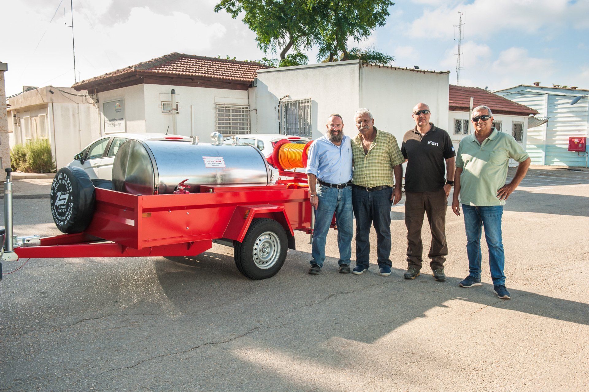 A group of men standing in front of a red trailer