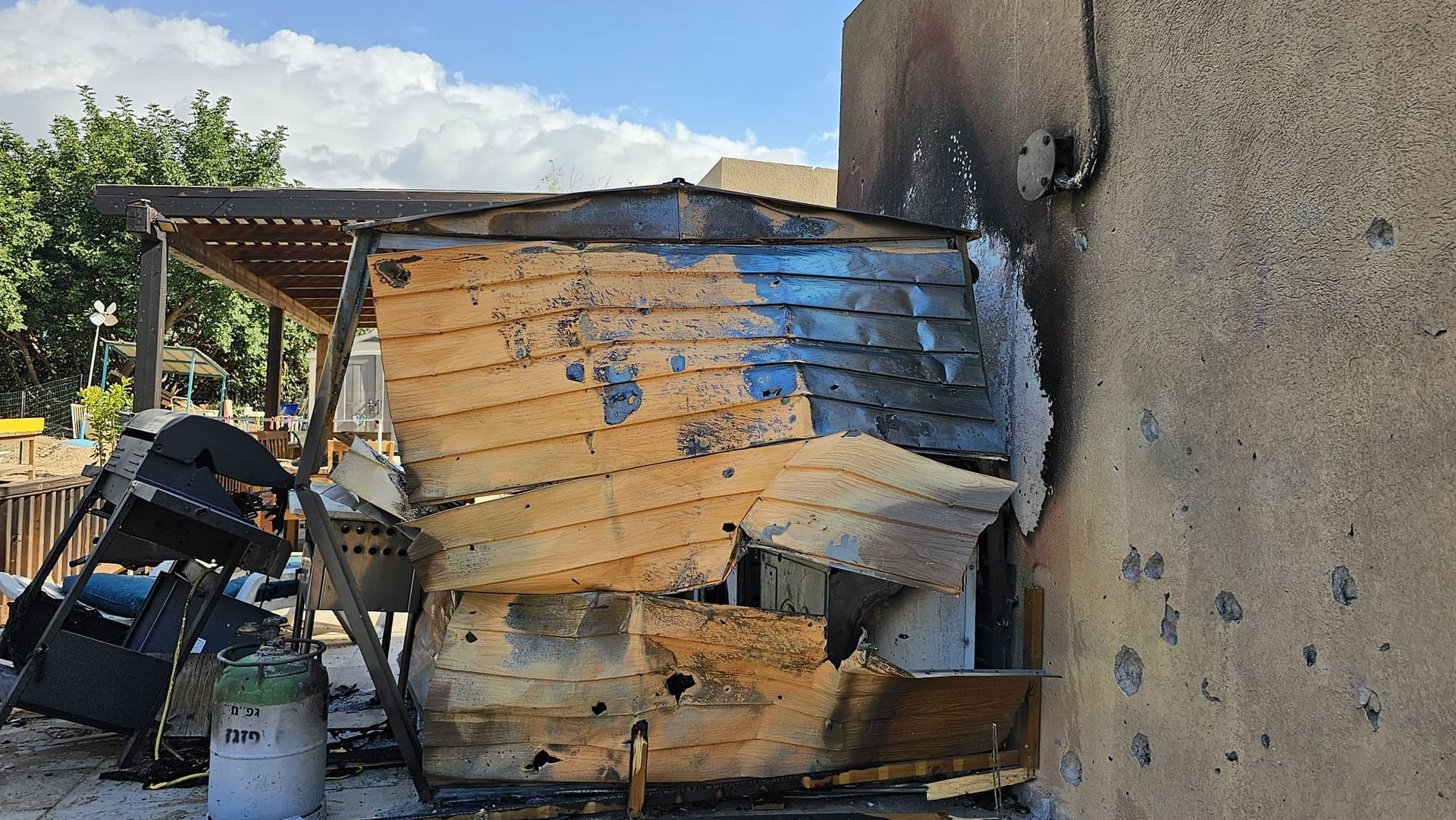 A wooden shed is sitting next to a concrete wall.