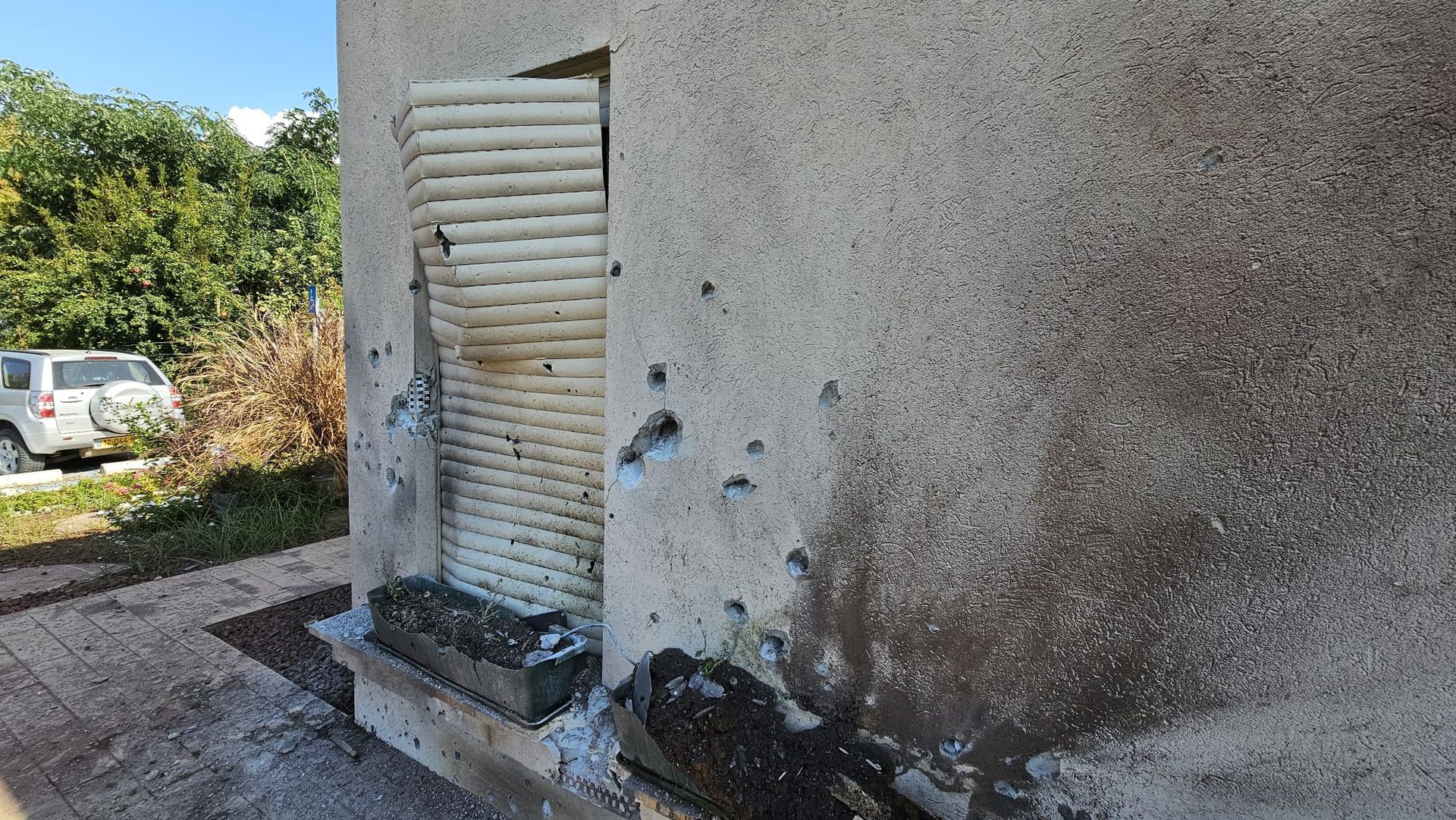 A gray wall with a white shutter on it